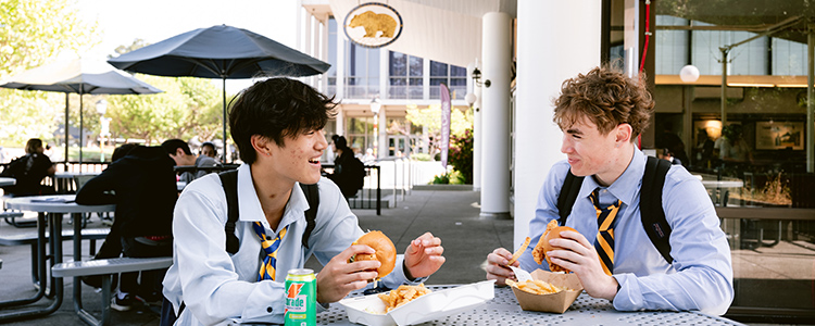 Students sit outside while chatting and enjoying their meals